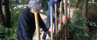 Volunteers construct a fence with natural materials