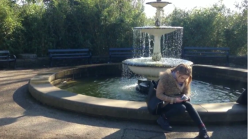 girl sitting by fountain