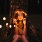 These well worn toys: girl sitting with a crown of fairy lights