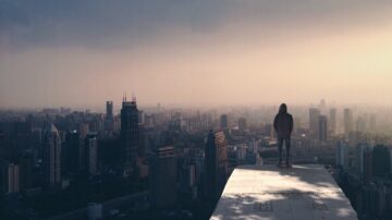 hooded person alone looking over a city