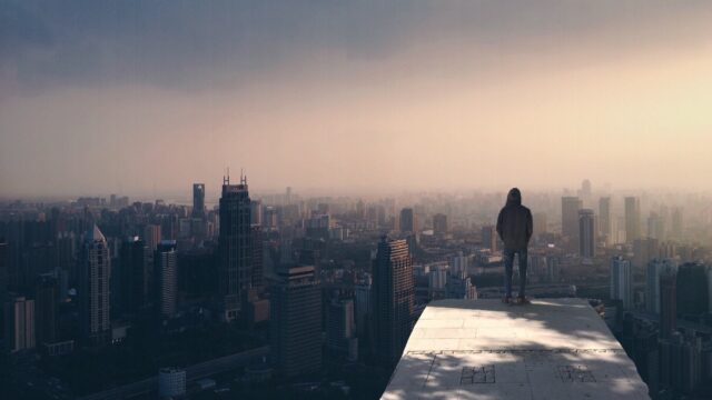 hooded person alone looking over a city