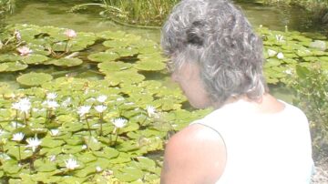 woman looking into a lily pond