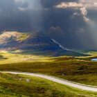 rolling landscape with light shining through stormy clouds