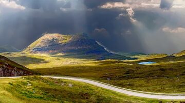 rolling landscape with light shining through stormy clouds