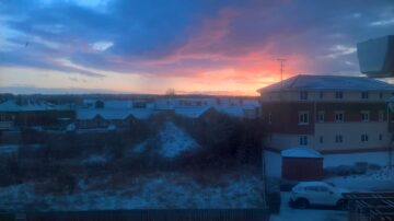 sun rising over snowy houses