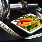 Small portion of food with a measuring tape and exercise weights