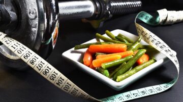 Small portion of food with a measuring tape and exercise weights