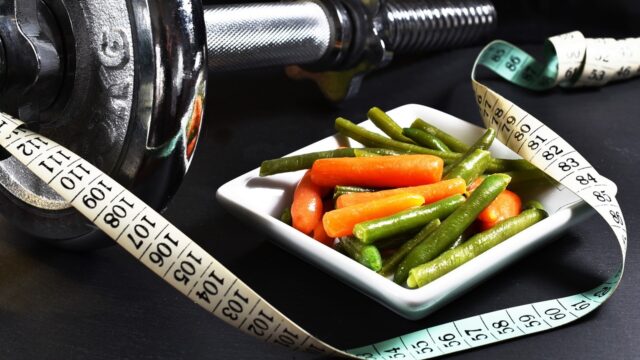 Small portion of food with a measuring tape and exercise weights