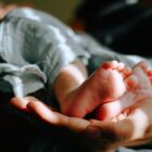 Baby being held in someones hands