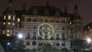 Happy face projected onto wall in peace gardens