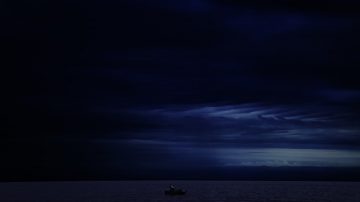 A small boat on a dark, calm ocean at night.