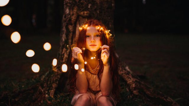 These well worn toys: girl sitting with a crown of fairy lights