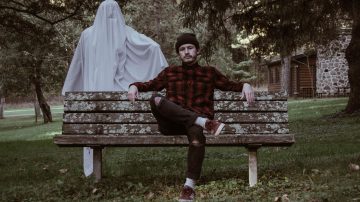 ghost stood behind a man on a bench