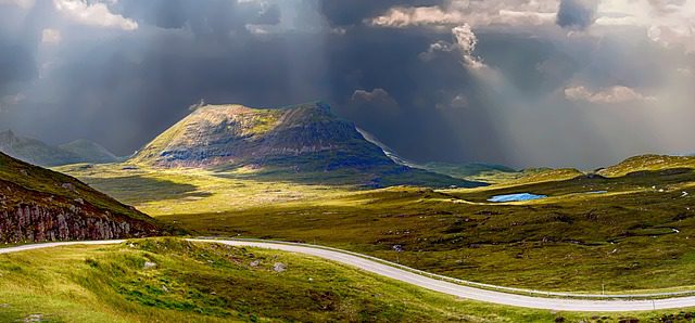 rolling landscape with light shining through stormy clouds