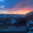 sun rising over snowy houses