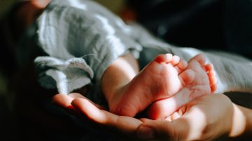 Baby being held in someones hands