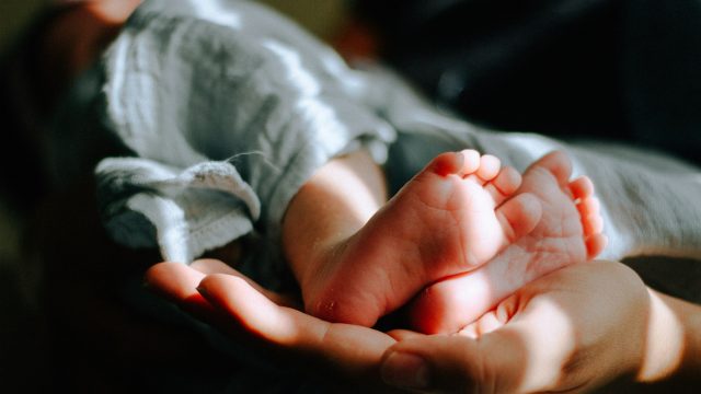 Baby being held in someones hands